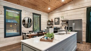 A modern kitchen with wooden walls, a central island, and a stainless steel refrigerator. - Relax'd Retreat Couples Cabin with Hot Tub-Fire Pit-View-Deck (Sevierville)