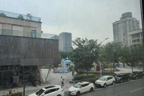A city street with modern buildings, parked cars, and a pedestrian crossing. - Xin'anjiang Hotel (Jiande)