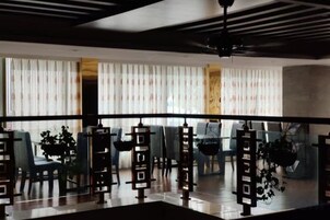 Un interior moderno con zona de estar, ventilador de techo y vistas a través de un panel de vidrio.