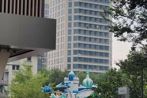 Un edificio de diseño moderno, con una fachada amplia y ventanas, y una estructura decorativa con detalles azules y blancos al frente.