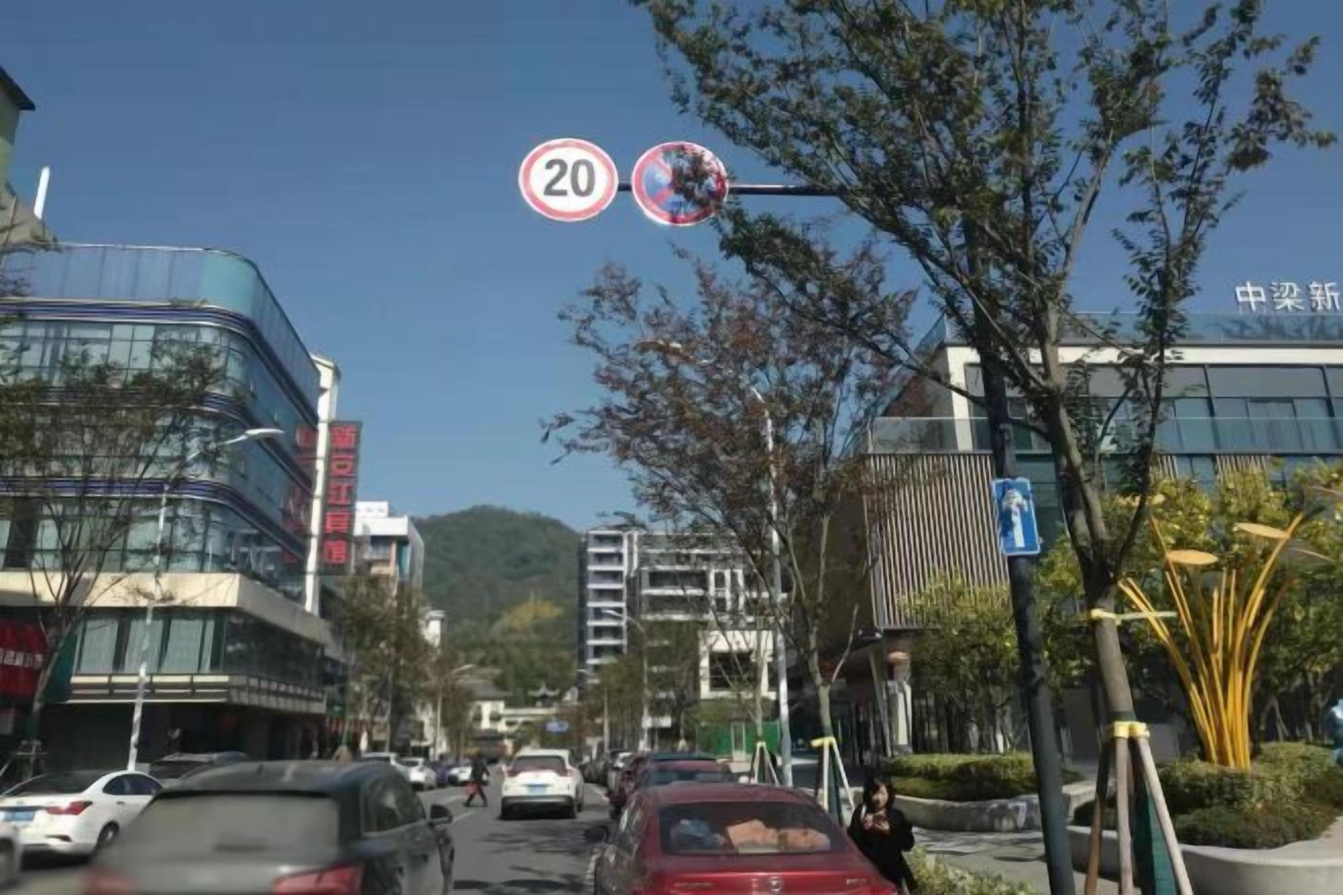 A street with buildings, cars, and a speed limit sign.