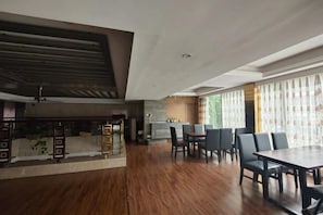 A spacious room with a wooden floor, a dining area with a table and chairs, and a large window with curtains. - Xin'anjiang Hotel (Jiande)