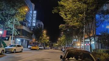 Una calle iluminada de noche, con coches aparcados y edificios con luz.