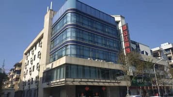 A multi-story building with a modern architectural design, featuring a prominent entrance with a glass facade and a visible sign.
