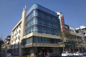 A multi-story building with a modern architectural design, featuring a prominent entrance with a glass facade and a visible sign. - Xin'anjiang Hotel (Jiande)