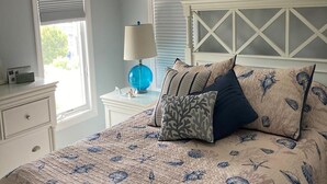 Ein Schlafzimmer mit einem Bett, einem Nachttisch, einer Lampe und einem Deckenventilator.