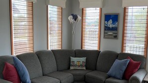 Ein modernes Wohnzimmer mit einer Eckcouch, einem Holztisch und einem grauen Teppich.