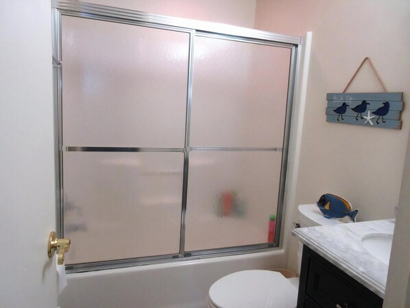 A bathroom with a glass shower enclosure, a toilet, and a vanity with a mirror.