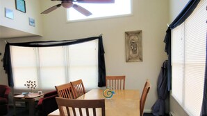 Un comedor con una mesa y sillas, un ventilador de techo y una ventana con persianas.