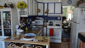 Cocina compacta con alacenas blancas, microondas, estufa y pileta.