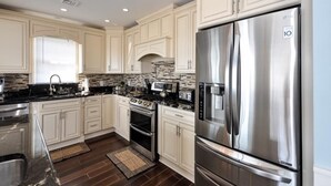 A modern kitchen with white cabinetry, a stainless steel refrigerator, a built-in oven, and a microwave. - VIEWS AND A POOL! PERFECT VACATION HOME! (Brant Beach)