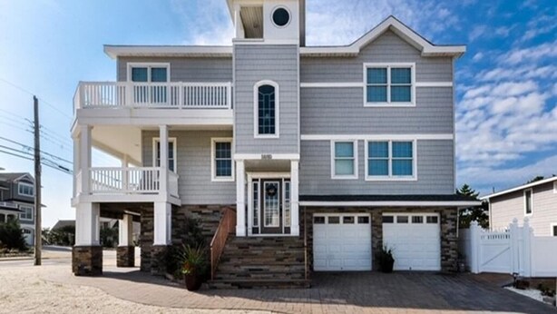 A two-story house with a balcony, a garage, and a stone accent wall. - VIEWS AND A POOL! PERFECT VACATION HOME! (Brant Beach)