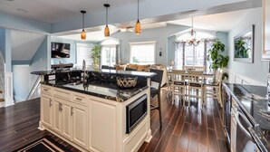A spacious kitchen with a large island, pendant lighting, and a dining area with a table and chairs. - VIEWS AND A POOL! PERFECT VACATION HOME! (Brant Beach)