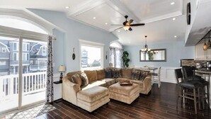 A spacious living room with a sectional sofa, a dining area with a table and chairs, and a view of the city through large windows. - VIEWS AND A POOL! PERFECT VACATION HOME! (Brant Beach)
