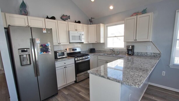 A modern kitchen with white cabinets, stainless steel appliances, and a granite countertop.
