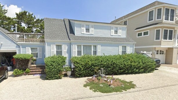 A two-story residential house with a front porch, a small garden with a decorative centerpiece, and a garage.
