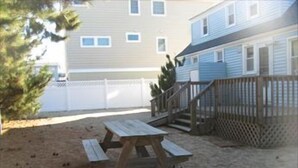 A backyard with a wooden picnic table and a wooden deck.