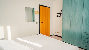 Ein Schlafzimmer mit Bett, Schrank, Spiegel und Tür.
