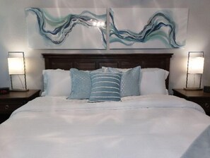 Relax in a serene space with a large bed, striped pillow, and two wall-mounted lamps.