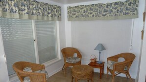 A room with wicker chairs, a small table with a lamp, and a window with a patterned valance. - Oceanside 3 Bedroom, 1 Bath Duplex - A Short Walk to the Beach! (Beach Haven Crest)