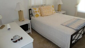 A bedroom with a bed, two bedside tables, two lamps, a decorative turtle, and a window with curtains. - Oceanside 3 Bedroom, 1 Bath Duplex - A Short Walk to the Beach! (Beach Haven Crest)
