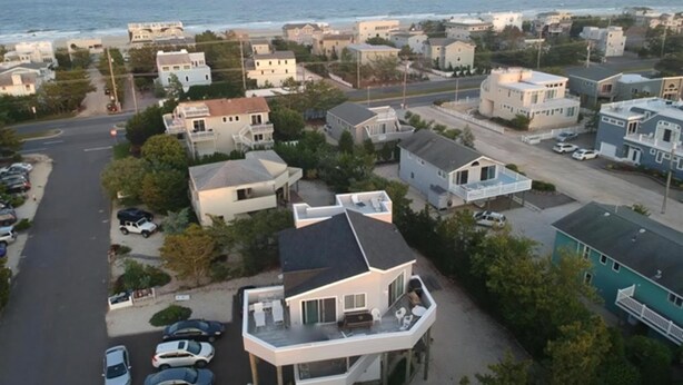 An aerial view of a coastal residential area with houses, a road, and a beach in the background. - 4 bedroom accommodation in North Beach (North Beach)
