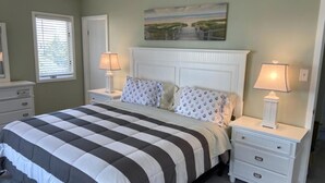A bedroom with a bed, two nightstands, a dresser, and a painting on the wall. - 4 bedroom accommodation in North Beach (North Beach)