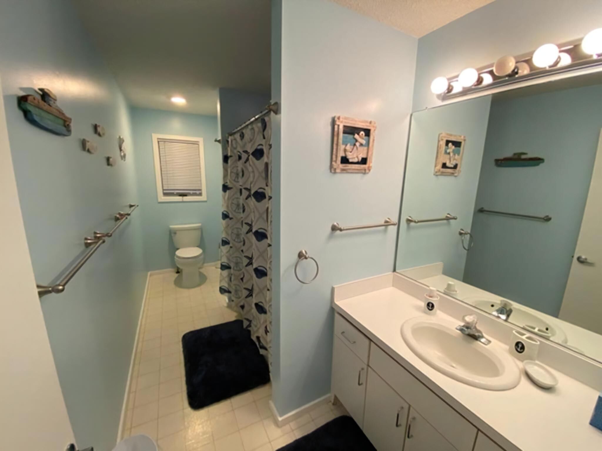 Une salle de bain équipée de toilettes, d’un lavabo, d’un miroir et d’un rideau de douche.