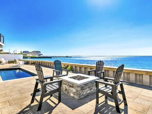Een terras buiten met een zwembad, zitplaatsen en uitzicht op zee.