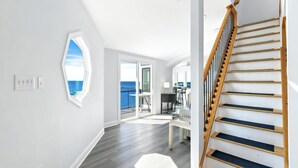 En rummelig indretning med en trætrappe, et stort vindue med udsigt og et moderne køkkenområde.