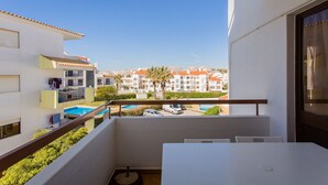 Un balcón con vistas a una piscina y edificios cercanos.