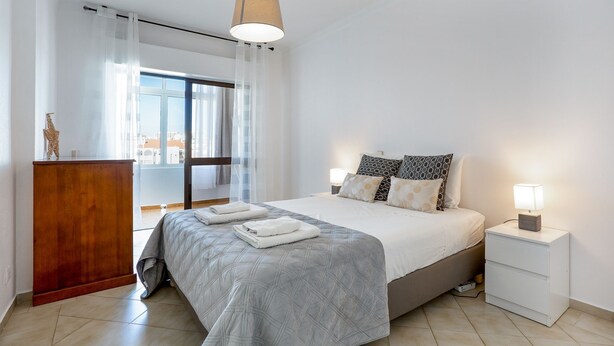 Una habitación de hotel moderna con una cama grande, un escritorio de madera y vistas de la ciudad a través de la ventana.
