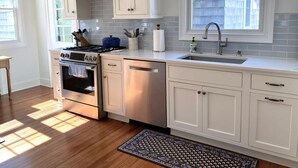 A kitchen with white cabinets, a stove, oven, and a sink. - LBI vacation rental property (Brant Beach)
