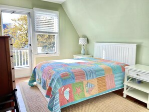 A bedroom with a bed, a nightstand, a dresser, a radiator, and a window with blinds. - LBI vacation rental property (Brant Beach)