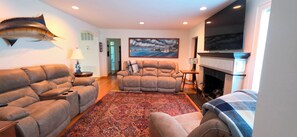 A living room with a fireplace, a large flat-screen TV, and a painting on the wall.