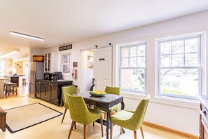 A modern kitchen with a dining area, large windows, and a coffee bar.
