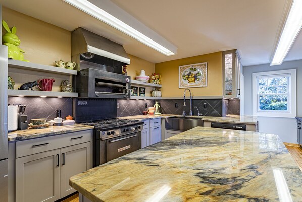 A modern kitchen with a central island, stainless steel appliances, and a variety of decorative items on shelves.