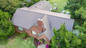 Uma casa com telhado inclinado, chaminé de tijolos e gramado bem cuidado.
