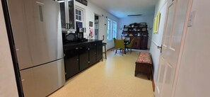 A kitchen with a refrigerator, microwave, and coffee maker. There is a dining area with chairs and a table.
