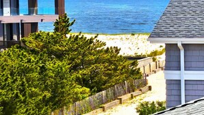 A coastal property with a view of the sea, a wooden deck, and a modern building structure. - Large Contemporary Ocean Block Home (Loveladies)