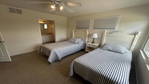 A bedroom with two beds, a ceiling fan, and a window with blinds. - Large Contemporary Ocean Block Home (Loveladies)