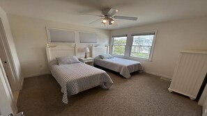 A bedroom with two beds, a ceiling fan, and a window with a view. - Large Contemporary Ocean Block Home (Loveladies)
