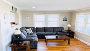 A living room with a sectional sofa, two coffee tables, a lamp, and a potted plant.