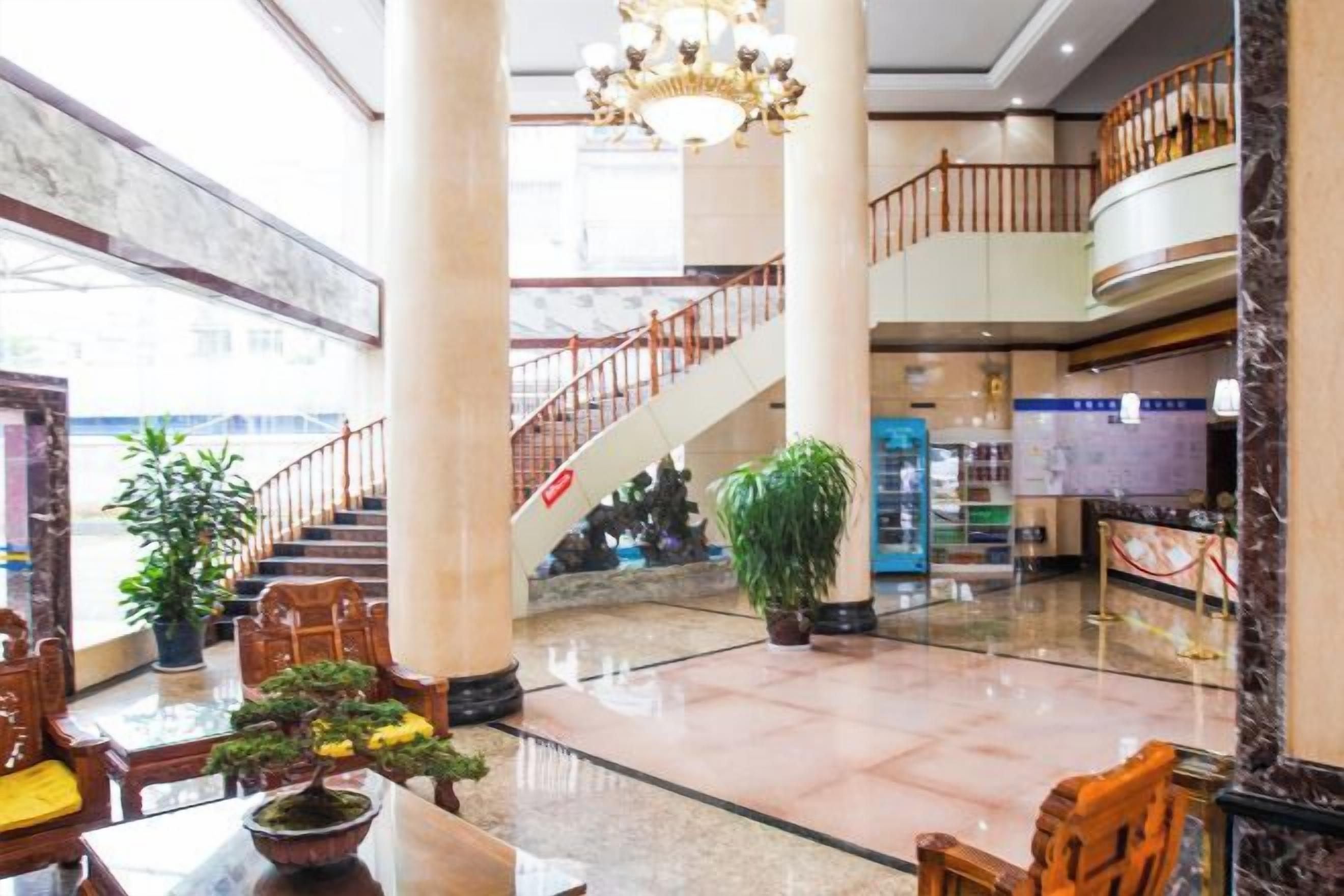 A spacious lobby with a marble floor, a staircase, and a reception desk.