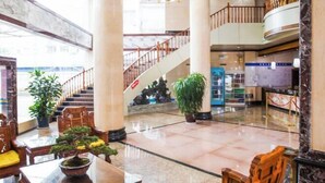 A spacious lobby with a marble floor, wooden furniture, potted plants, and a grand staircase. - Pu'er Kunman Hotel (Pu'er)