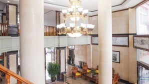 A lobby with a chandelier, wooden furniture, and large columns. - Pu'er Kunman Hotel (Pu'er)