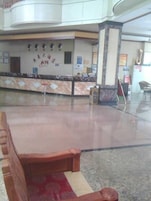 A hotel lobby with a reception desk, a wooden bench, and a marble floor.