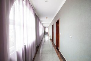 A long, narrow hallway with a carpeted floor, wooden doors, and large windows with curtains. - Pu'er Kunman Hotel (Pu'er)