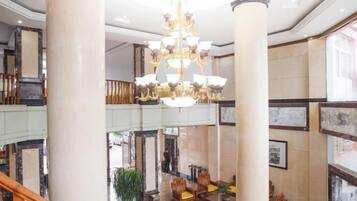Una hall con un lampadario, colonne e una scalinata.