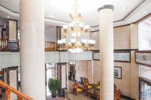 Un vestíbulo con una araña, columnas y una escalera.